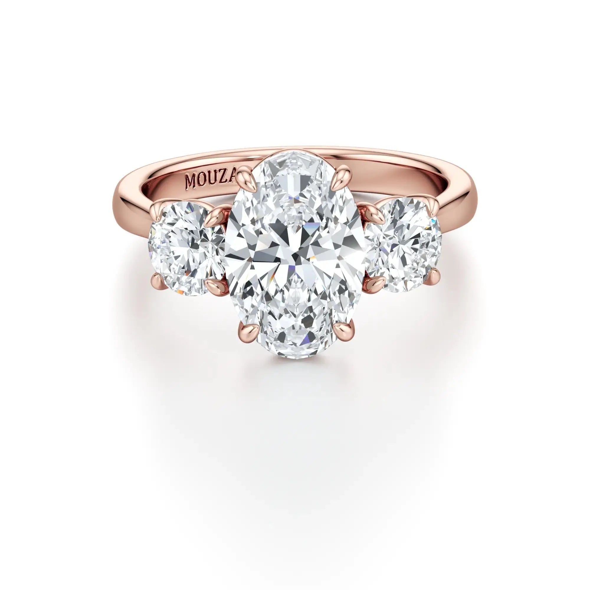 Rola - A classic three-stone engagement ring with round side stones and a central oval diamond, with 18K rose band having the brand name 'Mouza' on it.