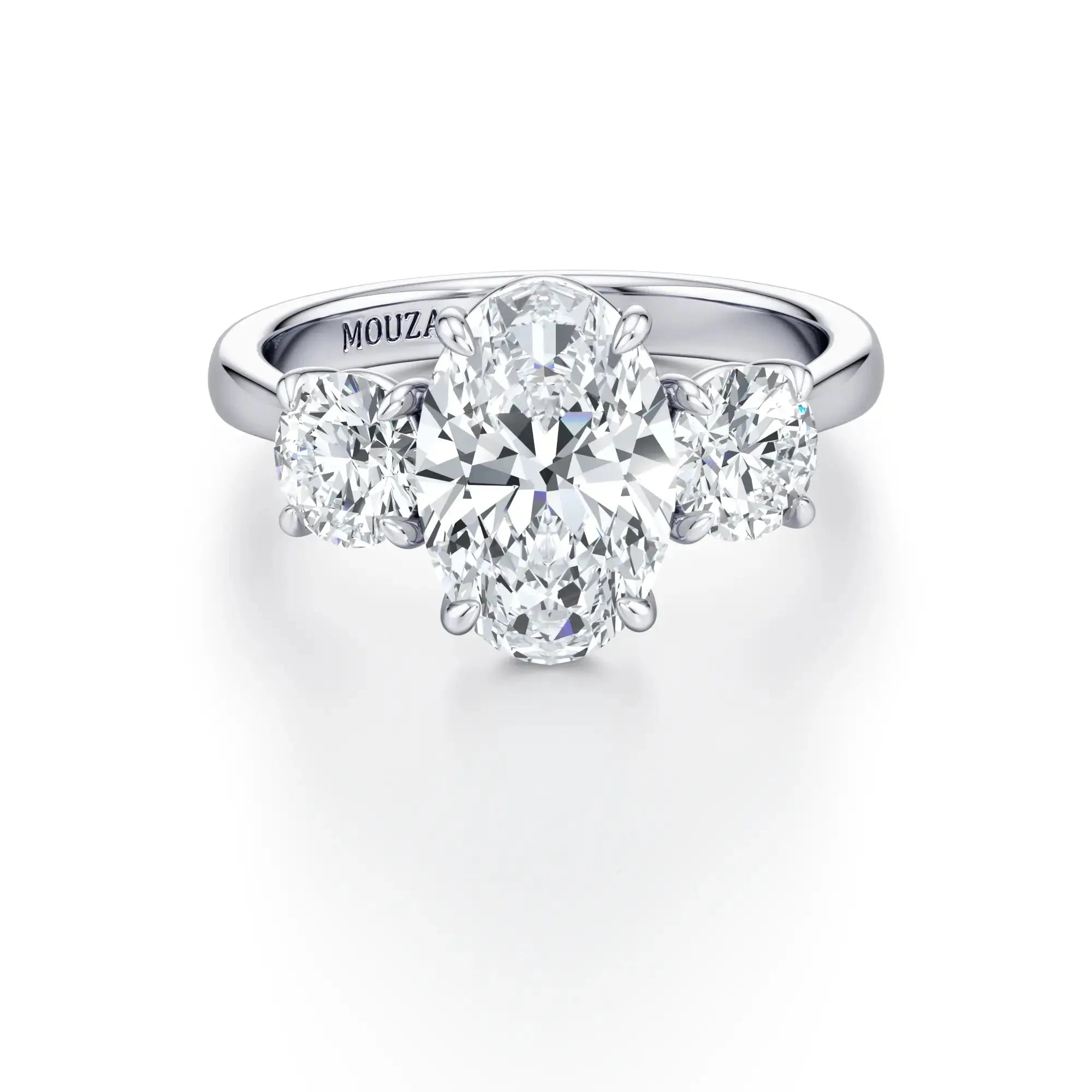 A classic three-stone engagement ring with round side stones and a central diamond, set in a cathedral-style setting with a tapered band in white gold.