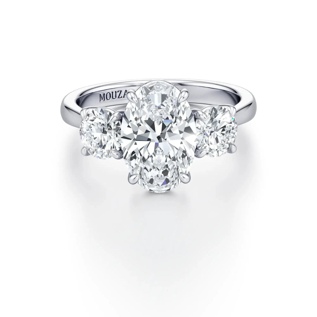 A classic three-stone engagement ring with round side stones and a central diamond, set in a cathedral-style setting with a tapered band in white gold.